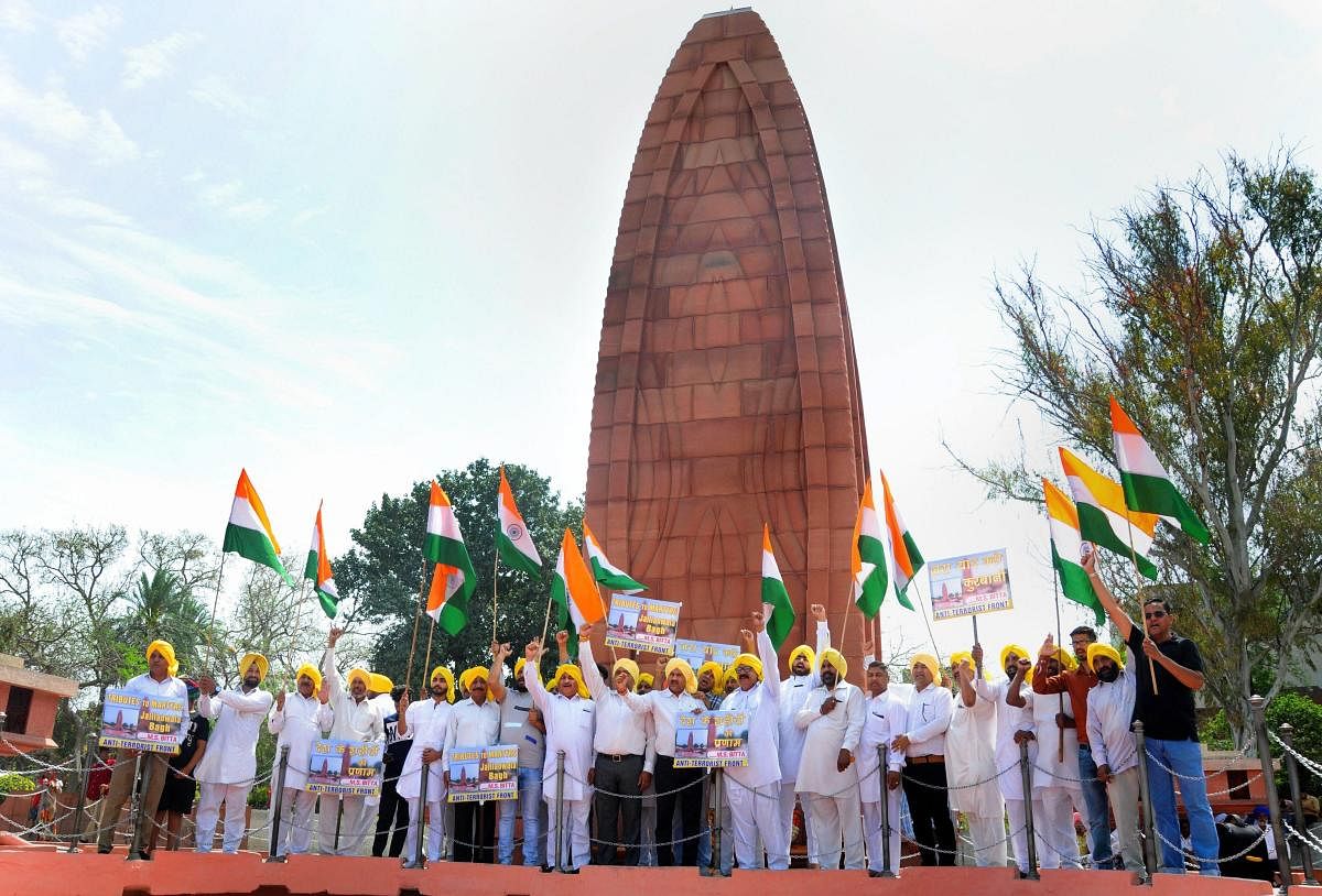 Activists of the All India Anti Terrorist Front (AIATF) hold Indian national flags as they shout patriotic slogans while paying tribute to the martyrs ahead of 100th anniversary of the JallianwalaBagh massacre, at its memorial in Amritsar on Thursday. PTI Photo