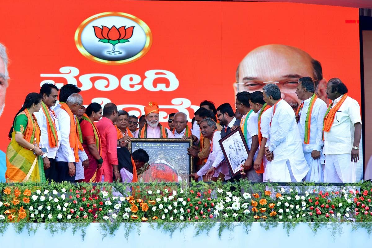 Prime Minister Narendra Modi is presented with a portrait of Anjaneya of Anjanadri, during the election rally in Gangavathi, Koppal district on Friday. DH Photo