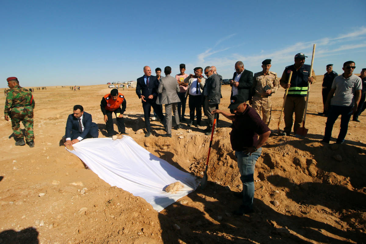 Iraqi members of the Civil Defense and officials cover the bones from an unearthed mass grave of Kurds in the west of the city of Samawa, Iraq. (Reuters Photo)