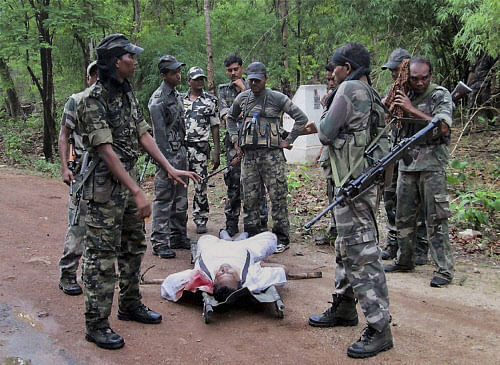 Security personnel stand near the body of one of the victims of Saturday's Maoist attack in a densely forested area in Bastar, about 345 kilometers (215 miles) south of Raipur, Chhattisgarh state, India, Sunday, May 26, 2013. Officials reacted with outrage Sunday to an audacious attack by about 200 suspected Maoist rebels who set off a roadside bomb and opened fire on a convoy carrying Indian ruling Congress party leaders and members in an eastern state, killing at least 24 people and wounding 37 others. (AP Photo)