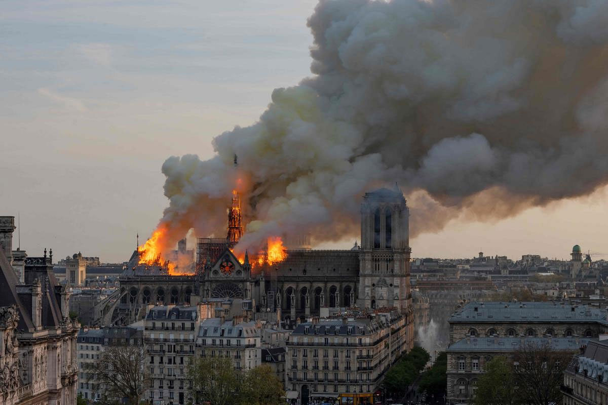 Smoke billows as flames burn through the roof of the Notre-Dame de Paris Cathedral on April 15, 2019, in the French capital Paris. - A huge fire swept through the roof of the famed Notre-Dame Cathedral in central Paris on April 15, 2019, sending flames and huge clouds of grey smoke billowing into the sky. The flames and smoke plumed from the spire and roof of the gothic cathedral, visited by millions of people a year. A spokesman for the cathedral told AFP that the wooden structure supporting the roof was being gutted by the blaze.  AFP photo
