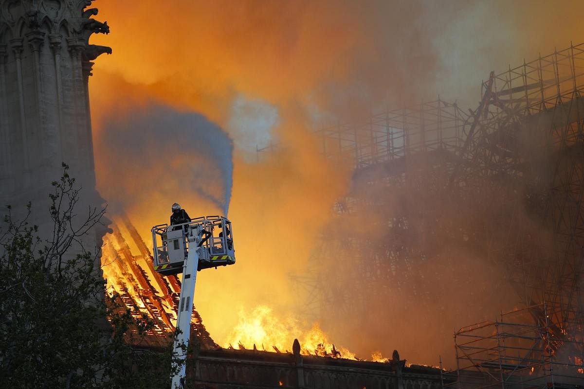 A fire fighter uses a hose as Notre Dame cathedral is burning in Paris, Monday, April 15, 2019. A catastrophic fire engulfed the upper reaches of Paris' soaring Notre Dame Cathedral as it was undergoing renovations Monday, threatening one of the greatest