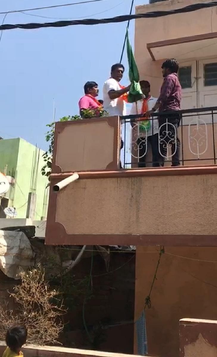 BJP corporator C R Ramamohan forcibly removes the flag from the first floor of a house at Viratnagar, Bommanahalli, on Monday.