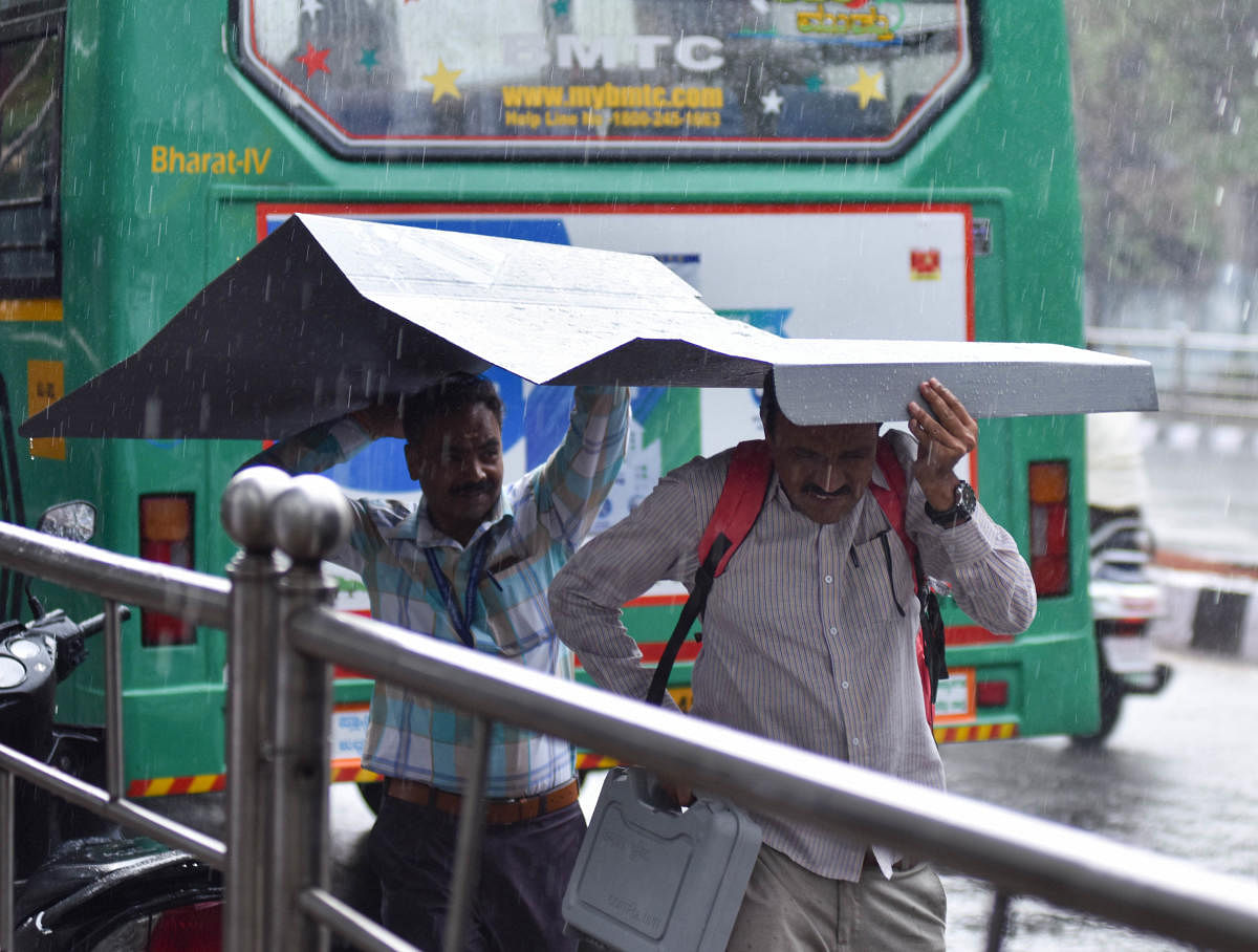 Sudden showers catch election officials unawares as they make their way to their polling booths ahead of the Lok Sabha elections in Bengaluru on Wednesday. DH Photo/ B H Shivakumar