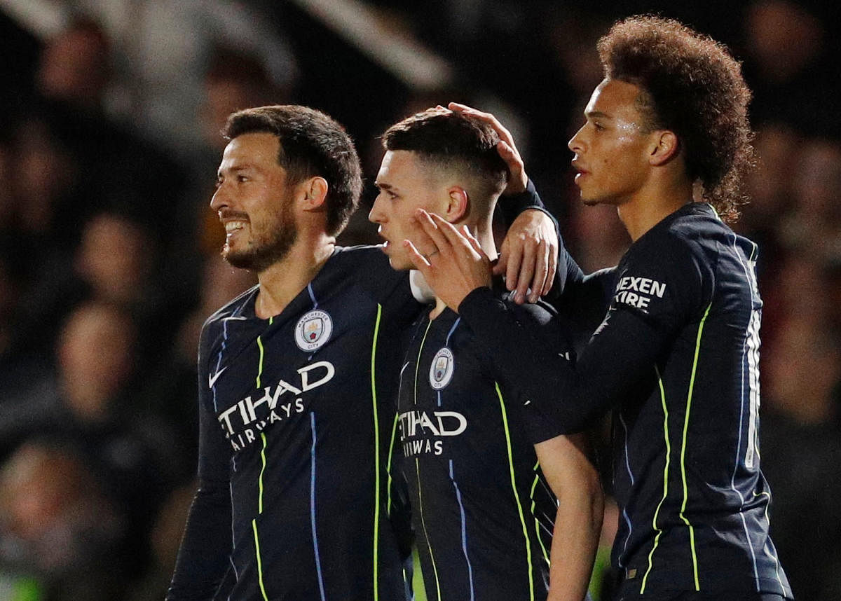 Manchester City's Phil Foden (centre) is congratulated by David Silva (left) and Leroy Sane after scoring against Newport County on Saturday. Reuters