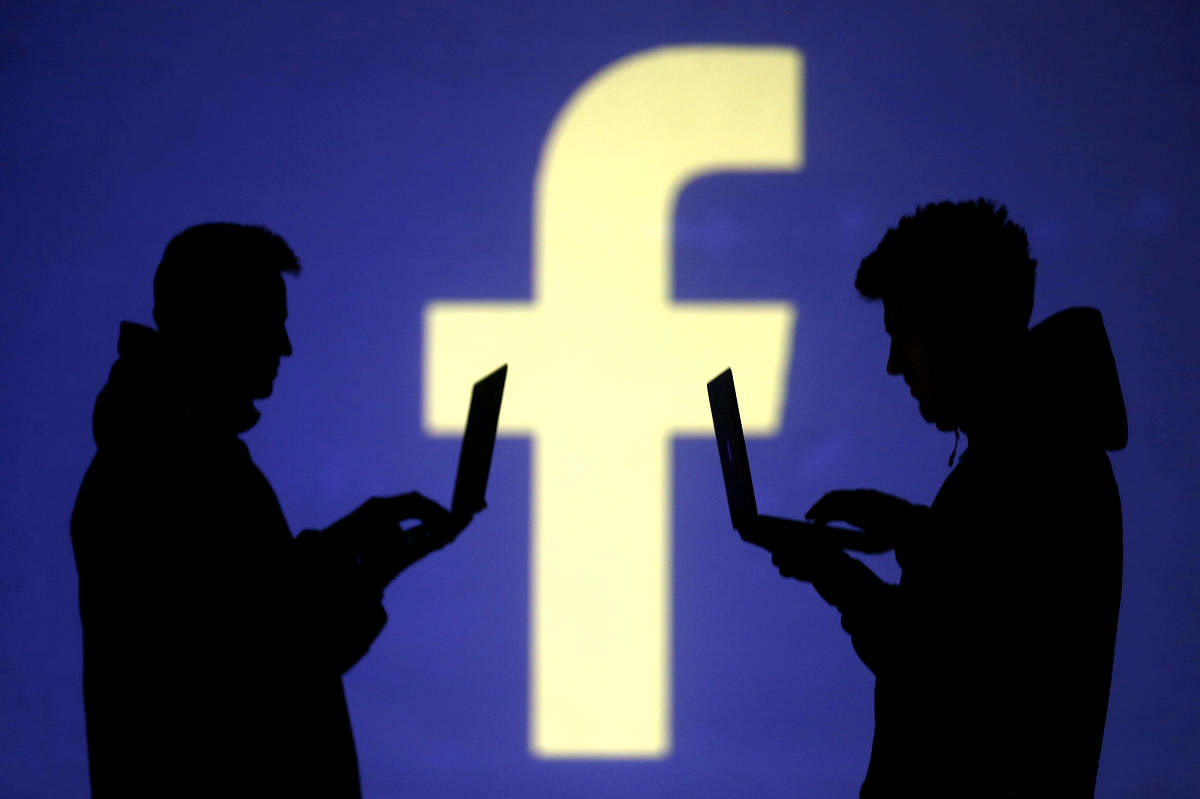 FILE PHOTO: Silhouettes of laptop users are seen next to a screen projection of Facebook logo in this picture illustration taken March 28, 2018. REUTERS/Dado Ruvic/Illustration/File Photo
