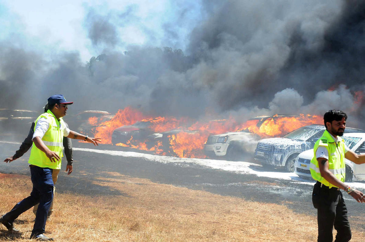 Civil Defence workers in action as the flames engulf cars. DH Photo