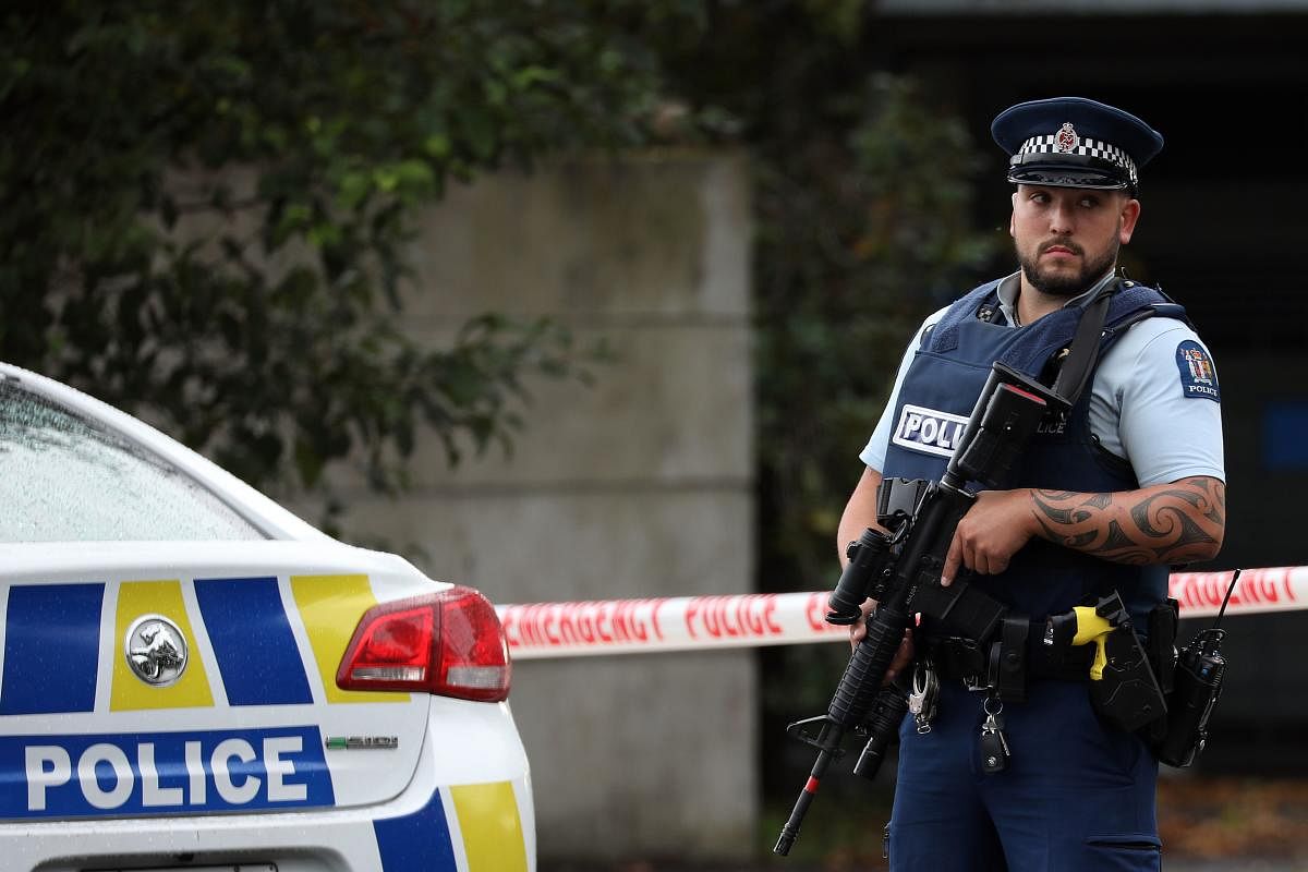 A policeman stands guard as others investigate a vehicle at the scene where a man died of stab wounds in Christchurch on March 27, 2019. - Christchurch police launched an urgent investigation on March 27 to find out whether a man who died after an early m