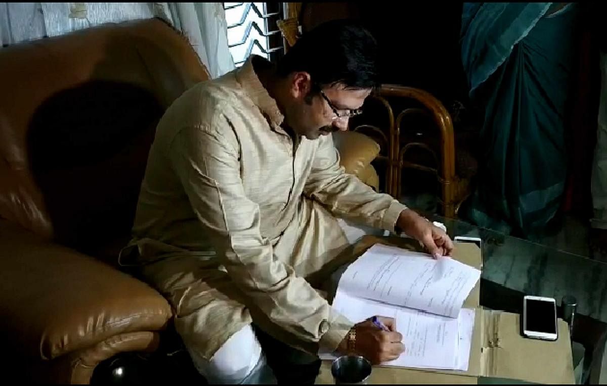 JD(S) nominee from Uttara Kannada Lok Sabha constituency Anand Asnotikar, following the advice by the family priest, signs nomination papers at the designated time at his house in Karwar on Saturday. DH PHOTO
