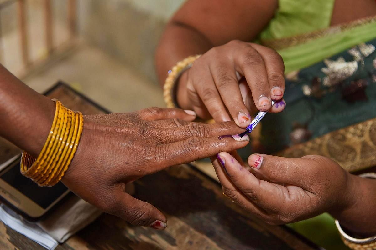 An election officer puts an indelible ink mark on the finger of a voter after she cast her vote during the first phase of the general elections. PTI Photo