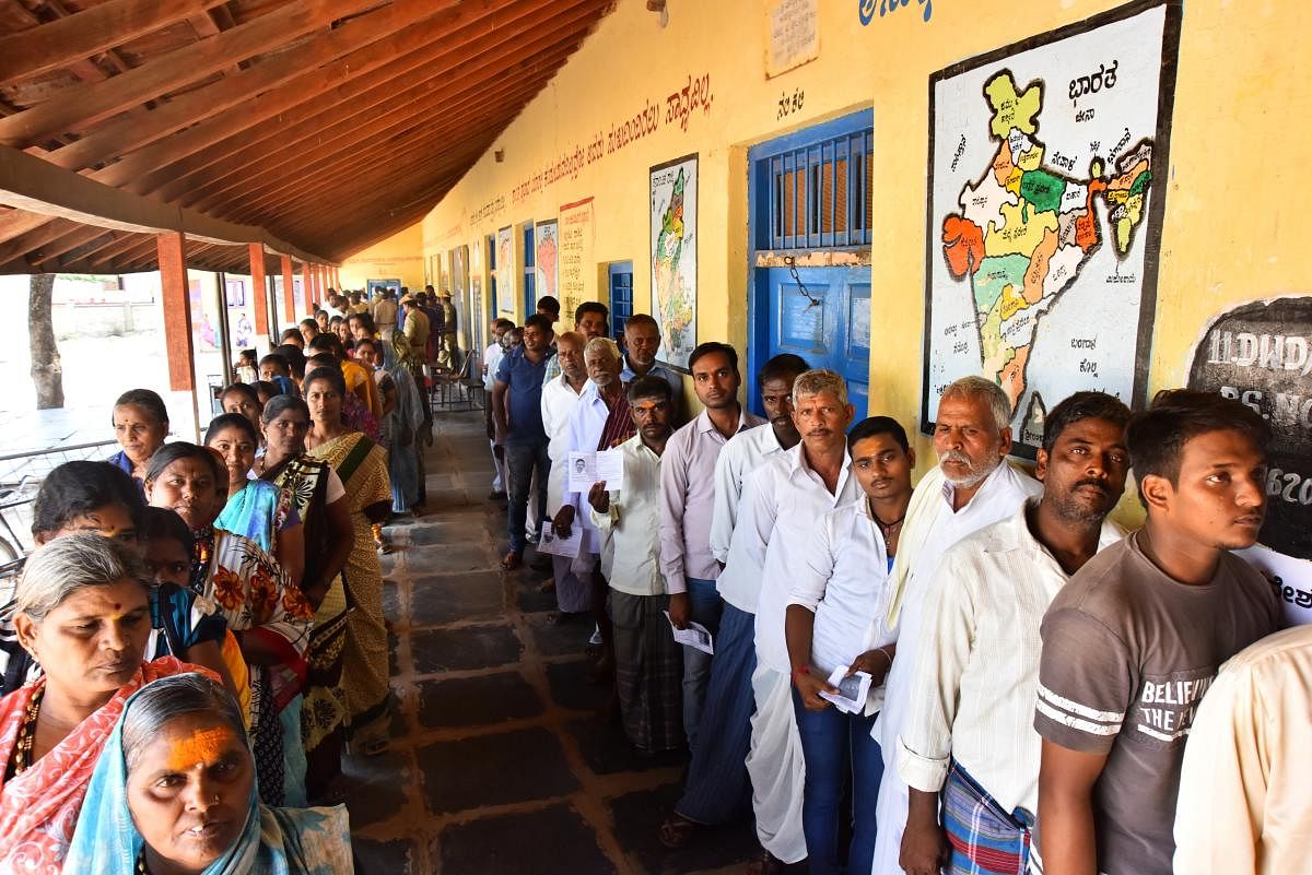 Voters wait in a queue to exercise their franchise at a polling booth in Nalavadi village of Annageri taluk, Hubballi, on Tuesday. DH Photo / Tajuddin Azad
