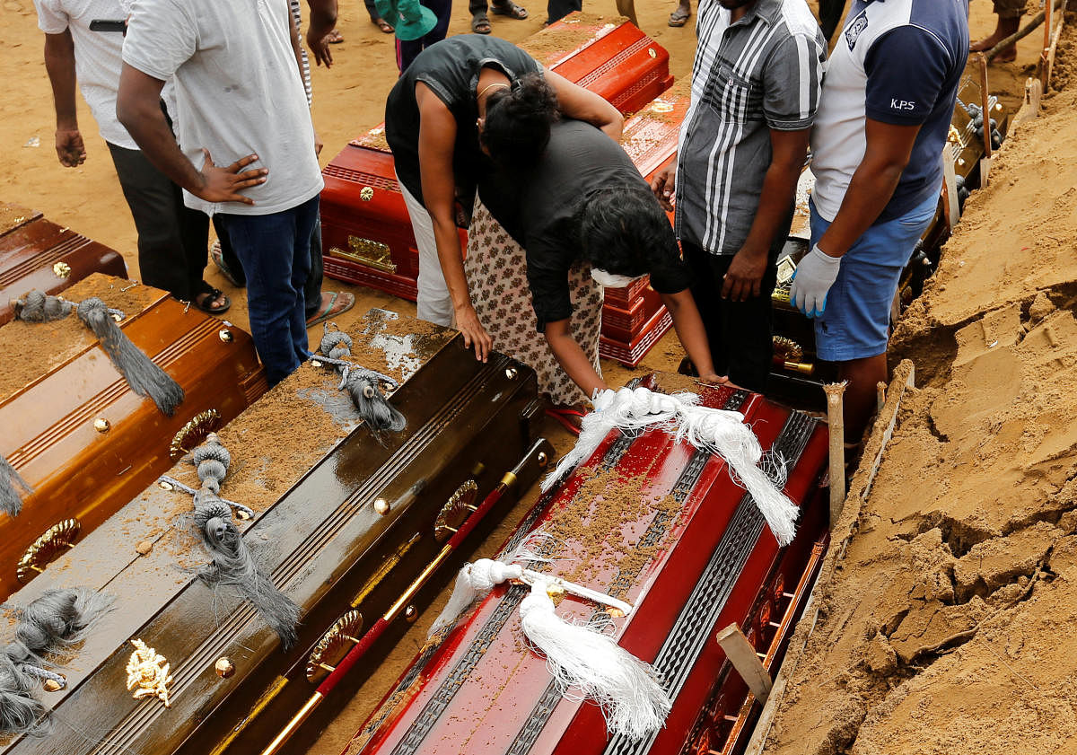 Coffins are laid in the ground during a mass burial for victims at a cemetery near St Sebastian's Church in Negombo, three days after a string of suicide bomb attacks on churches and luxury hotels across the island on Easter Sunday, in Sri Lanka April 24,