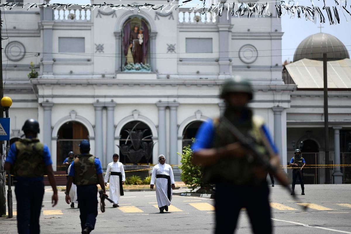 Priests walk on a blocked street as soldiers stand guard outside St. Anthony's Shrine in Colombo on April 25, 2019, following a series of bomb blasts targeting churches and luxury hotels on the Easter Sunday in Sri Lanka. - All of Sri Lanka's Catholic chu