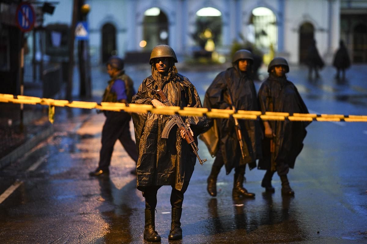 Sri Lankan soldiers stand guard under the rain at St. Anthony's Shrine in Colombo on April 25, 2019, following a series of bomb blasts targeting churches and luxury hotels on the Easter Sunday in Sri Lanka. - Sri Lanka's Catholic church suspended all publ