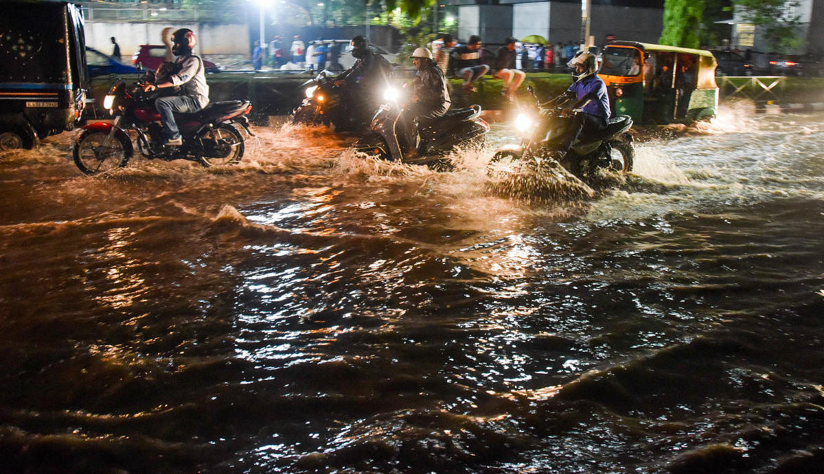 Cubbon Park near the metro station was flooded following the downpour on Tuesday. (Right, below) Two women stranded near Chinnaswamy Stadium. DH PHOTOS/B K JANARDHAN