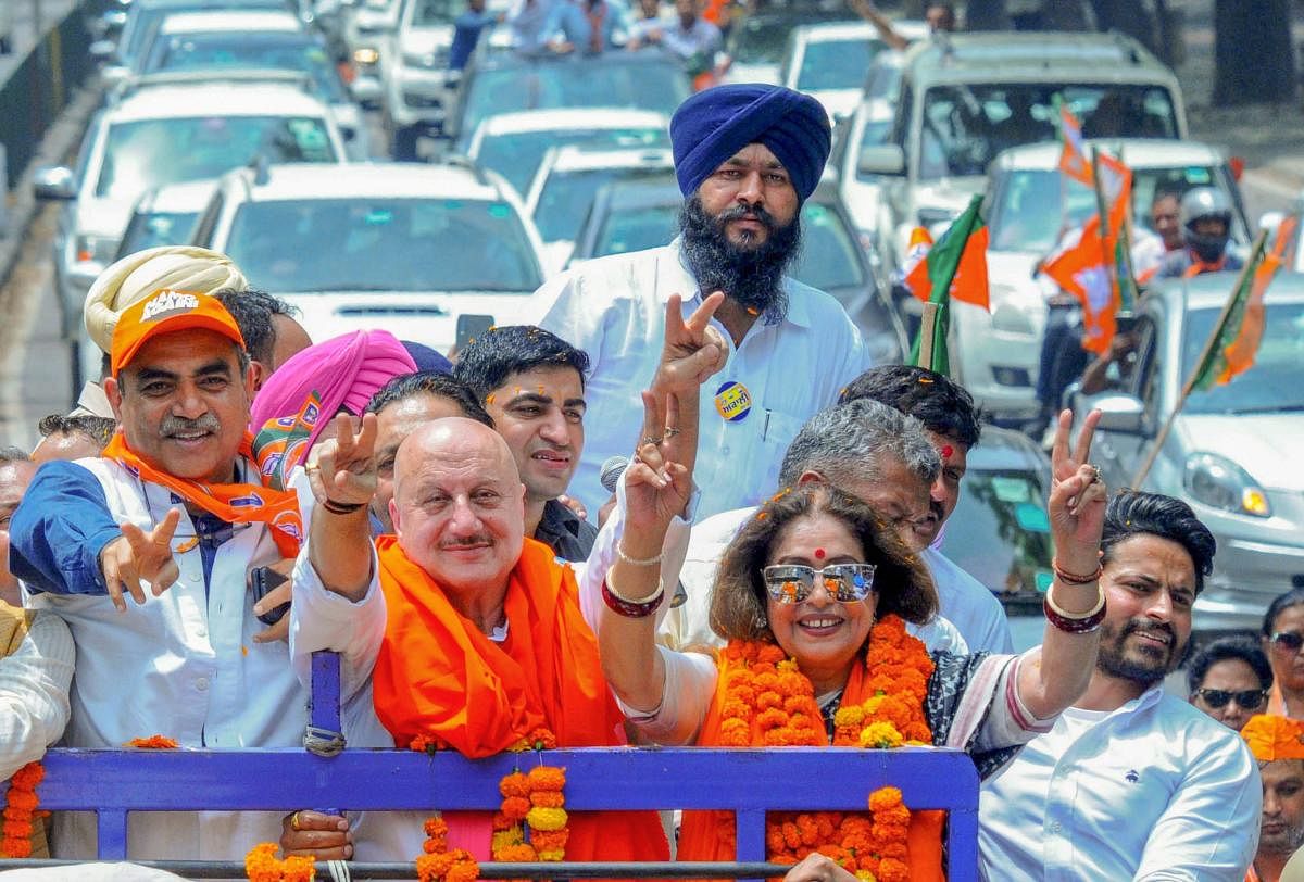 Chandigarh: Bollywood actor and sitting MP Kirron Kher along with her husband actor Anupam Kher and others flashes the victory sign during a roadshow before filing her nomination papers for the Lok Sabha polls, in Chandigarh, Thursday, April 24, 2019. (PT