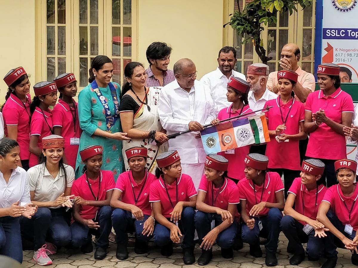 Minister G T Devegowda hands over the flags to the tribal girls in Mysuru, recently. Secretary of Tiger Adventure Foundation Suma Mahesh and chairman D S D Solanki are seen.