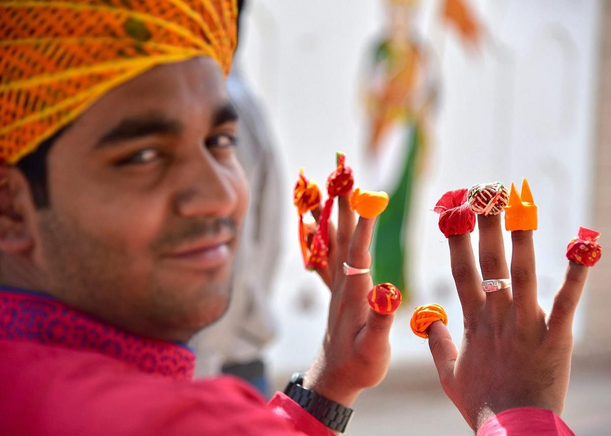 Artist Pawan Vyas, poses with miniatures of Rajasthani turbans, in Bikaner on March 29. PTI