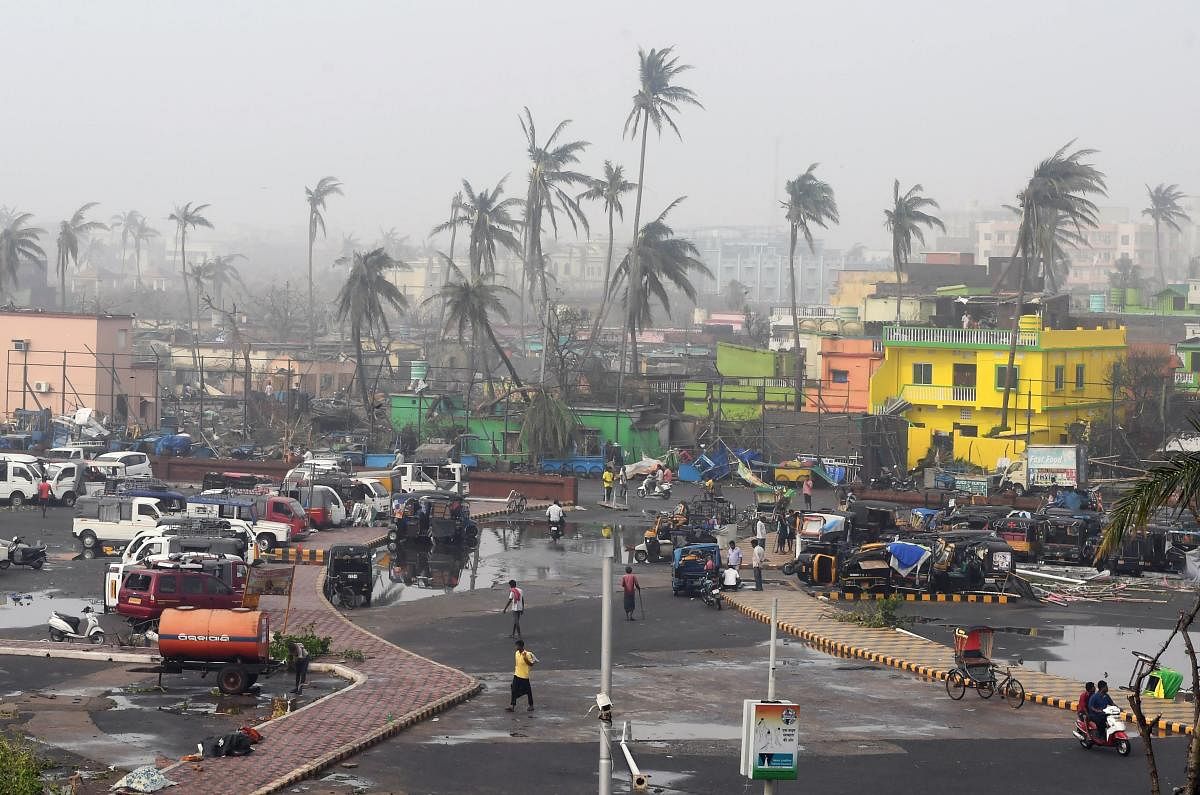 People gather next to storm-damaged buildings and palm trees in Puri in the eastern Indian state of Odisha. AFP photo