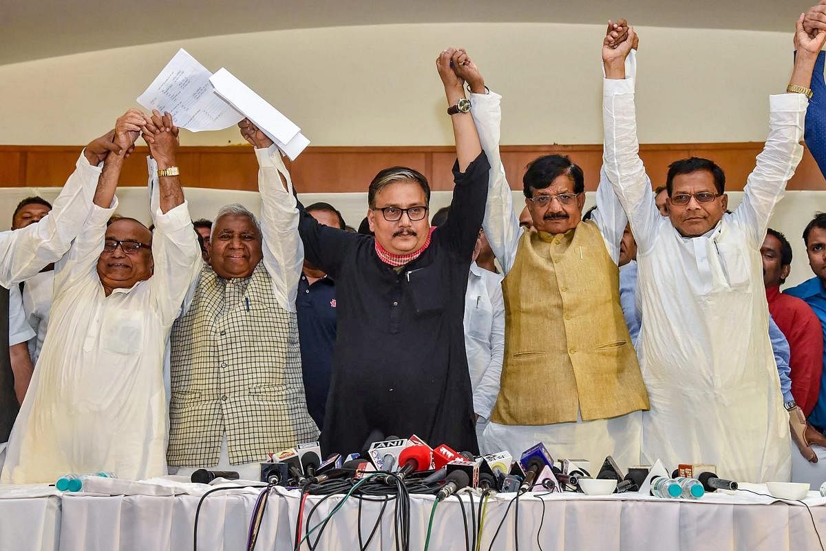 Rashtriya Janata Dal MP Manoj Jha, state's party President Ramchandra Purbey and Congress' state president Madan Mohan Jha join hands after announcing the grand alliance's candidates list for upcoming Lok Sabha election 2019, in Patna on March 22, 2019. (PTI Photo) 