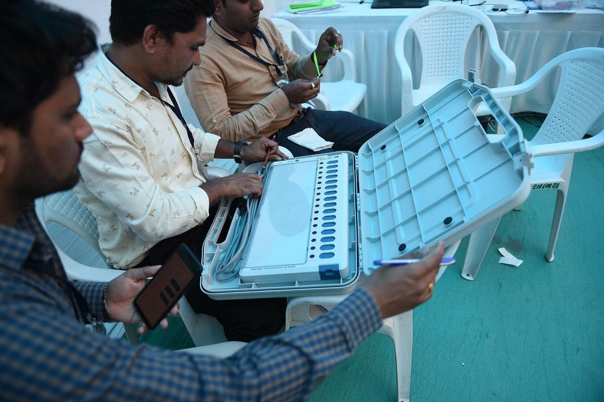Election officials check an Electronic Voting Machine (EVM) at a distribution centre ahead of the Lok Sabha elections in Ahmedabad. AFP