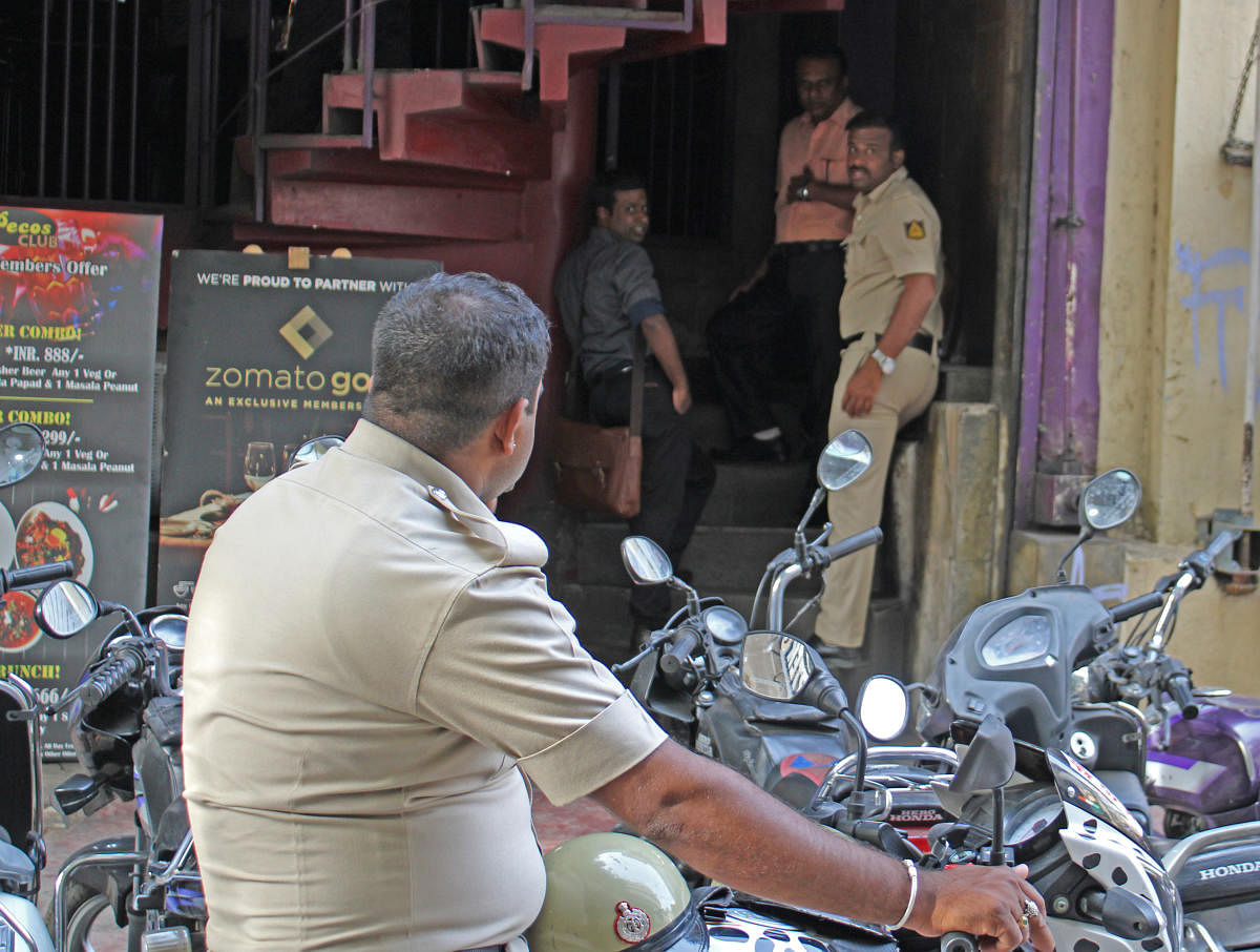 Policemen inspect CCTV cameras at a bar on Brigade Road in Bengaluru on Saturday. DH Photo/Madan K