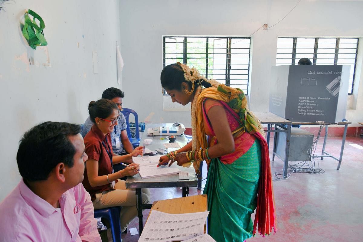 Maneesha (24) casts her vote after her wedding at a polling booth in Bengaluru on Thursday. AFP