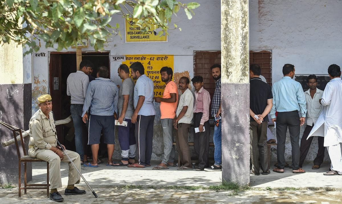 Voters wait in a queue to cast their votes at a polling station, during a first phase of voting for the 2019 Lok Sabha elections, at Bisahada near Noida on Thursday. PTI photo