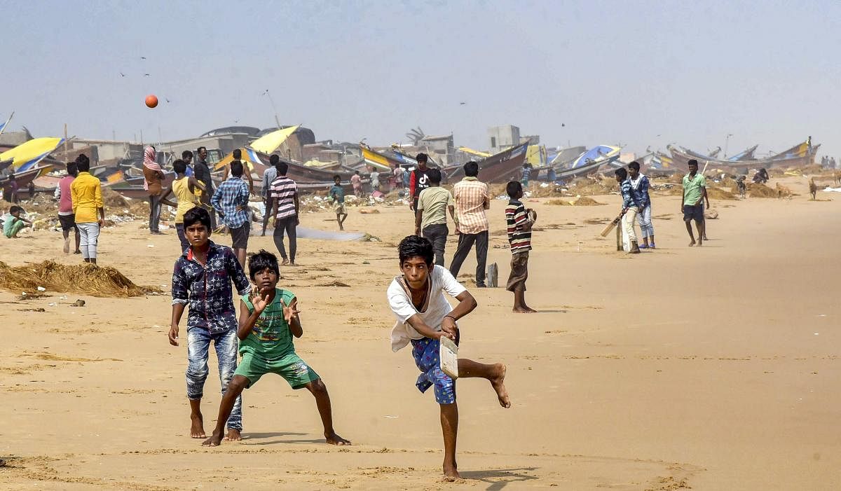 Puri: Fishermen community children play cricket at a field in the backdrop of boats damaged by Cyclone Fani, at Penthakata village in Puri, Wednesday, May 8, 2019. (PTI Photo) (PTI5_8_2019_000171B)