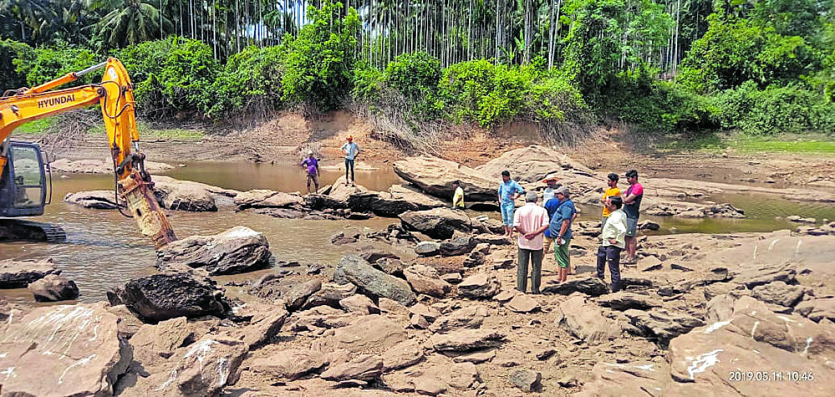 An earth mover pressed to service to remove silt and boulders to facilitate easy flow of water from River Swarna to Baje dam in Udupi.