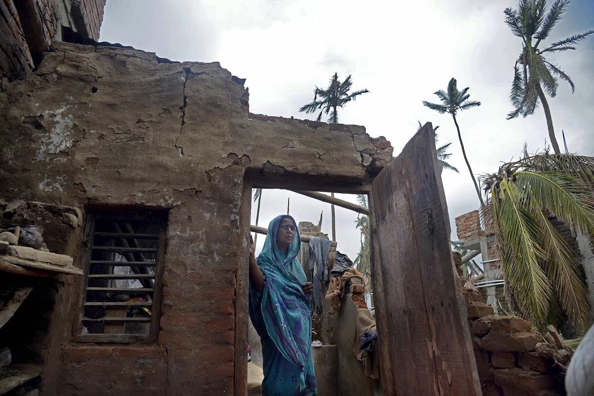 Puri: A woman stands in the remnants of her home in the aftermath of the cyclone 'Fani', at the heritage crafts village Raghurajpur, in Puri district. (PTI File Photo)