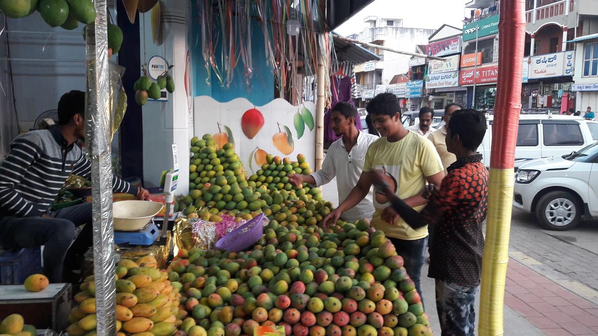 Customers buy mangoes at a stall on M G Road in Chikkamagaluru.