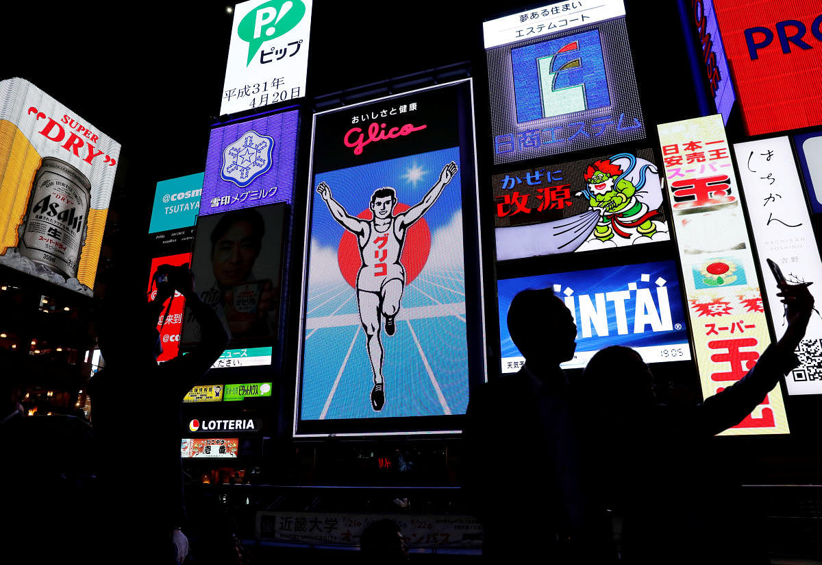 People take pictures in front of advertisements in the Dotonbori shopping and amusement district in Osaka, Japan, April 20, 2019 (File photo REUTERS).