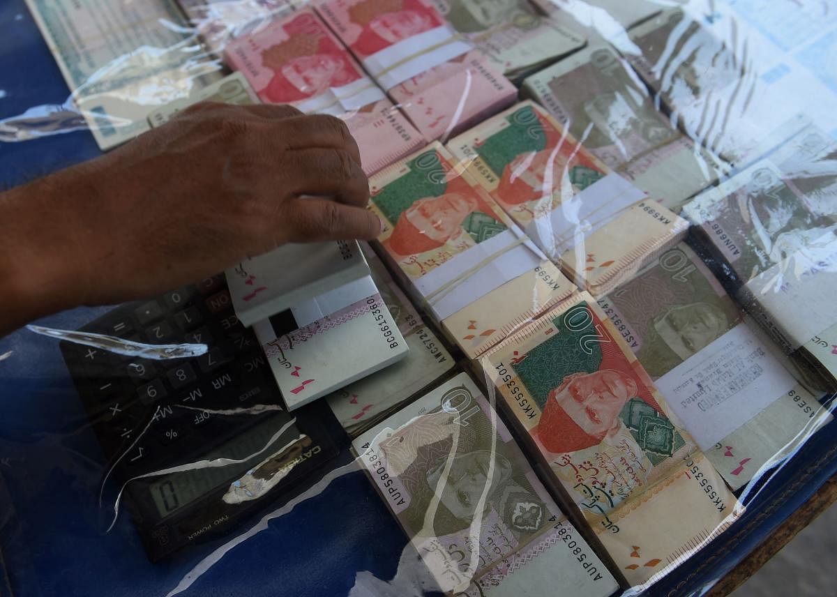 A currency exchange vendor adjusts Pakistani currency notes as he waits for customers on a street in Karachi on May 13, 2019. (AFP File Photo)