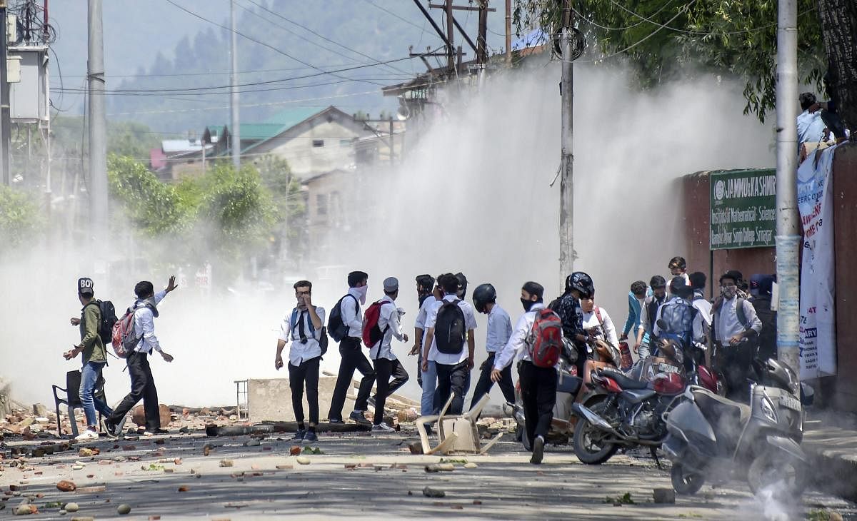 Srinagar: College students pelt stones at policemen amid tear gas during a protest against the alleged rape of a three-year-old girl by a local in Srinagar. (PTI Photo)