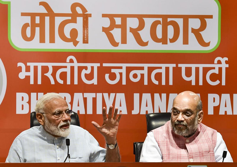 Prime Minister Narendra Modi speaks as BJP President Amit Shah looks on during a press conference at the party headquarters in New Delhi. (PTI Photo)