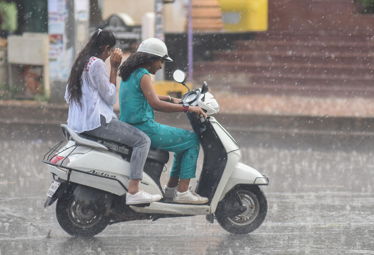Sudden rain in city, people seen protecting themselves with umbrella, vehicle riders move in rain. File photo