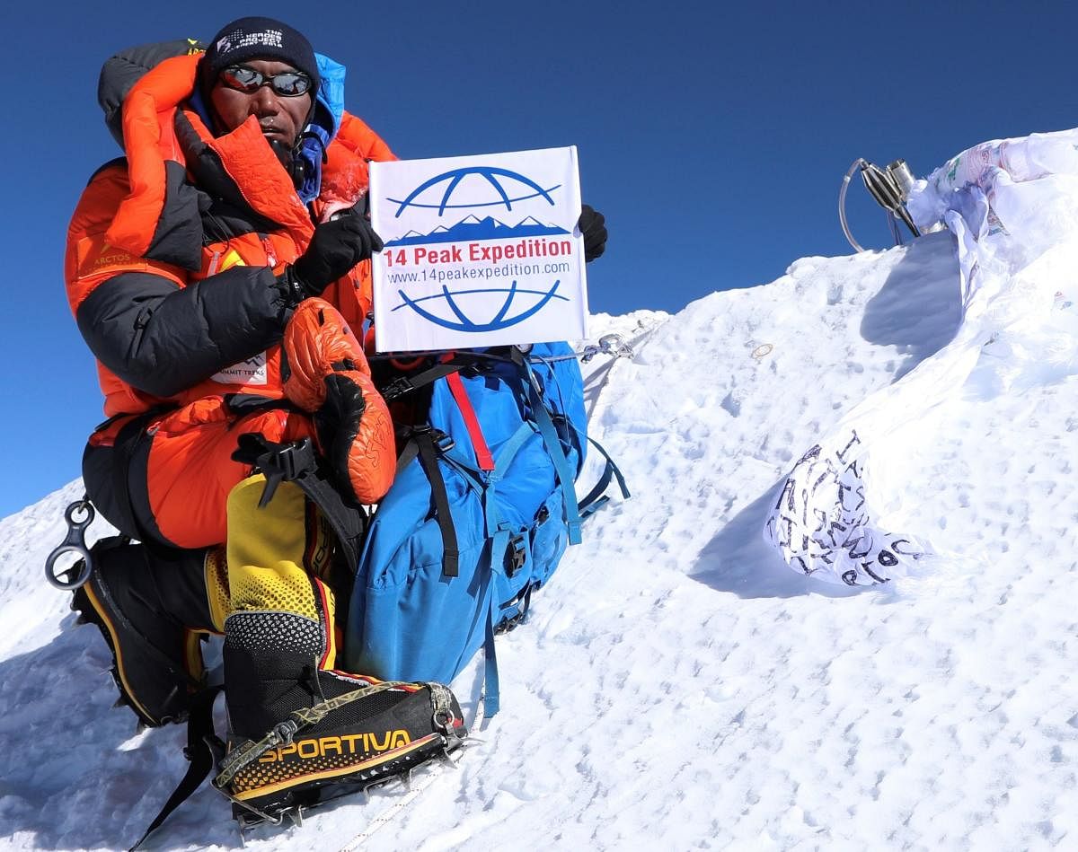 Nepali mountaineer Kami Rita Sherpa posing at the top of Mount Everest after summiting it for the 23rd time, breaking his own world record set last year. (Photo by AFP)