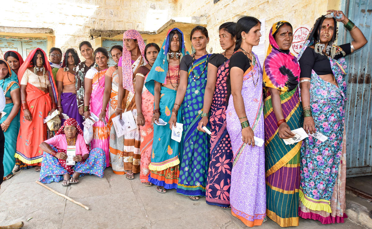 Women wait in a queue to exercise their franchise in the bypoll, at a polling booth at Koravi Dodda tanda in Chincholi Assembly constituency, Kalaburagi district, on Sunday. DH Photo/Prashanth H G