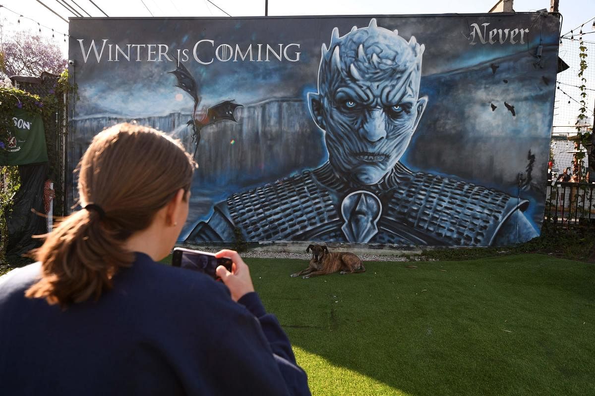A woman takes a photo of her dog in front of a "Game of Thrones" mural outside Brennan's bar before a viewing party for HBO's "Game of Thrones" series finale in Marina del Rey, California, May 19, 2019. (Photo AFP)