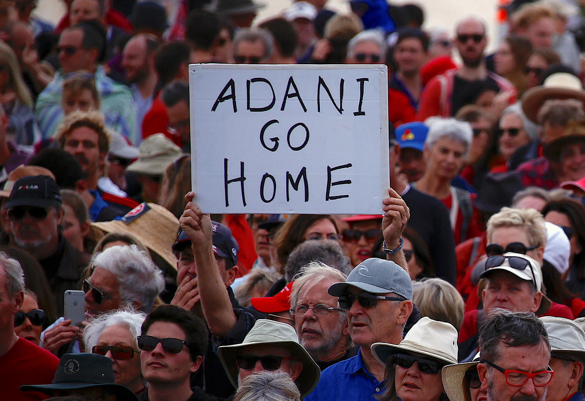 A protester holds a sign as he participates in a national Day of Action against the Indian mining company Adani's planned coal mine project in north-east Australia, at Sydney's Bondi Beach in Australia. (Reuters File Photo)