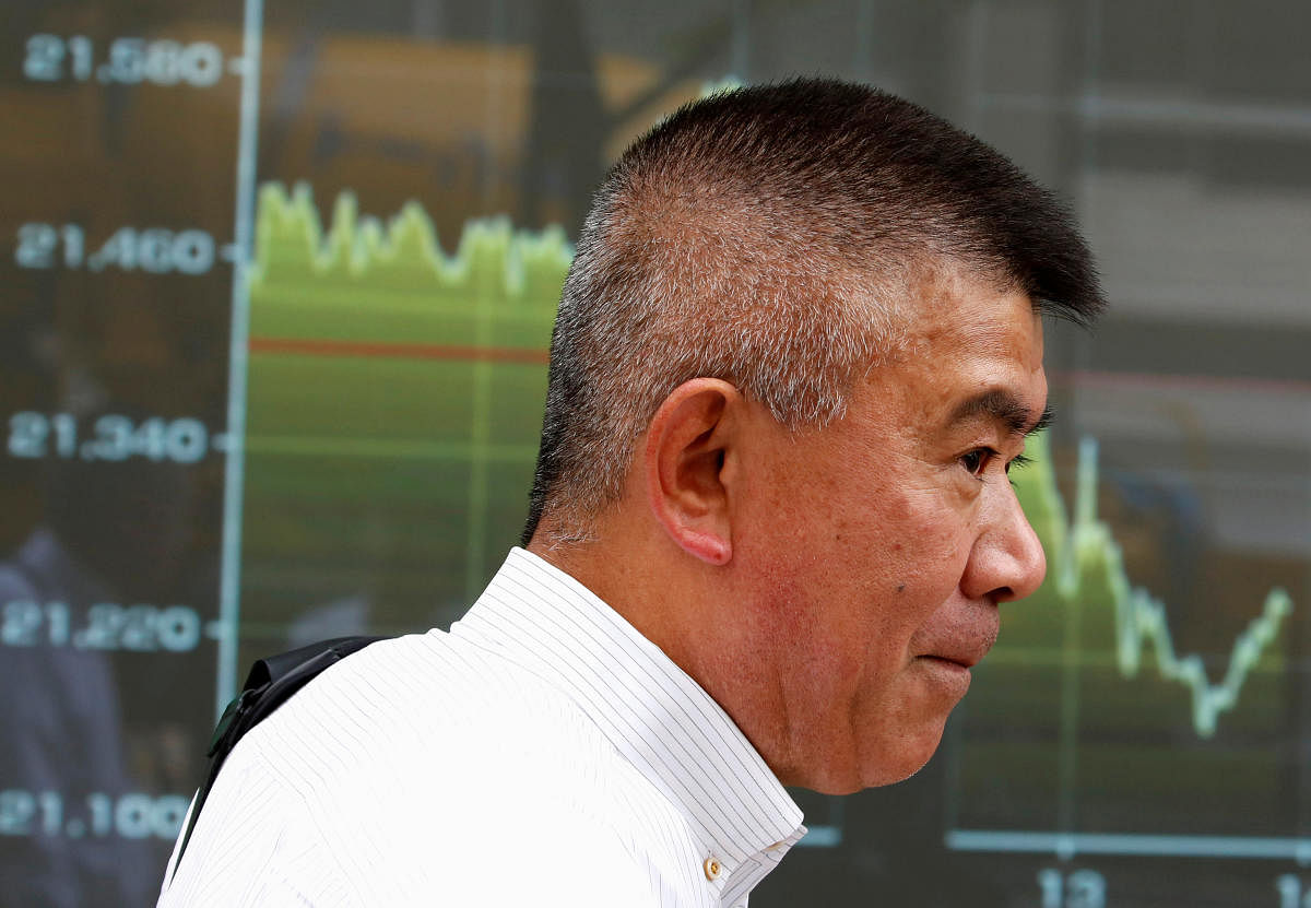A passerby stands in front of an electronic board displaying a graph showing recent movement of Japan's Nikkei average outside a brokerage in Tokyo. Reuters