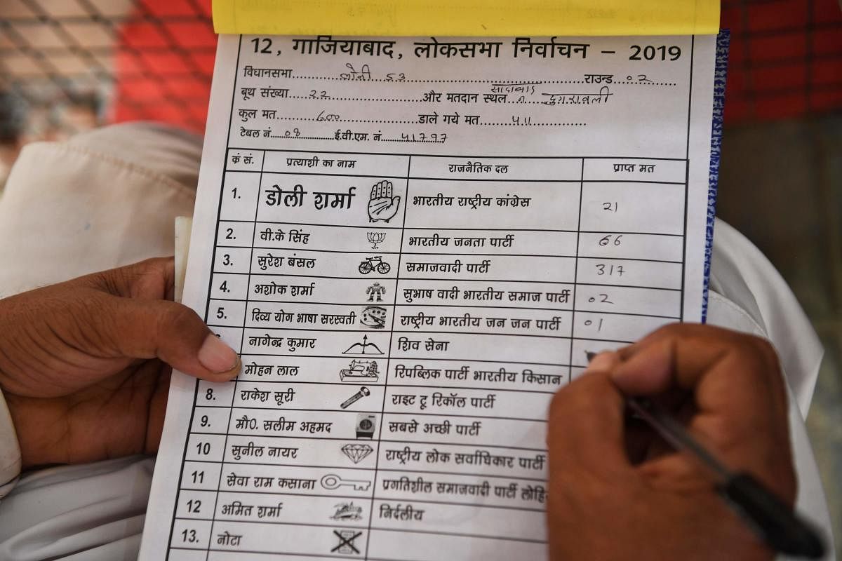 An Indian poll agent notes down details of votes that candidates got after the first round of counting at a counting centre in Ghaziabad. (Photo AFP)