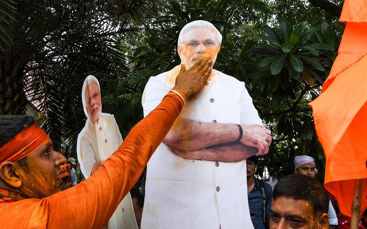 An Indian Bharatiya Janata Party (BJP) supporter puts colour on a cut-out of Indian Prime Minister Narendra Modi as he celebrates on the vote results day for India's general election at BJP headquarters in New Delhi on May 23, 2019. - Prime Minister Naren