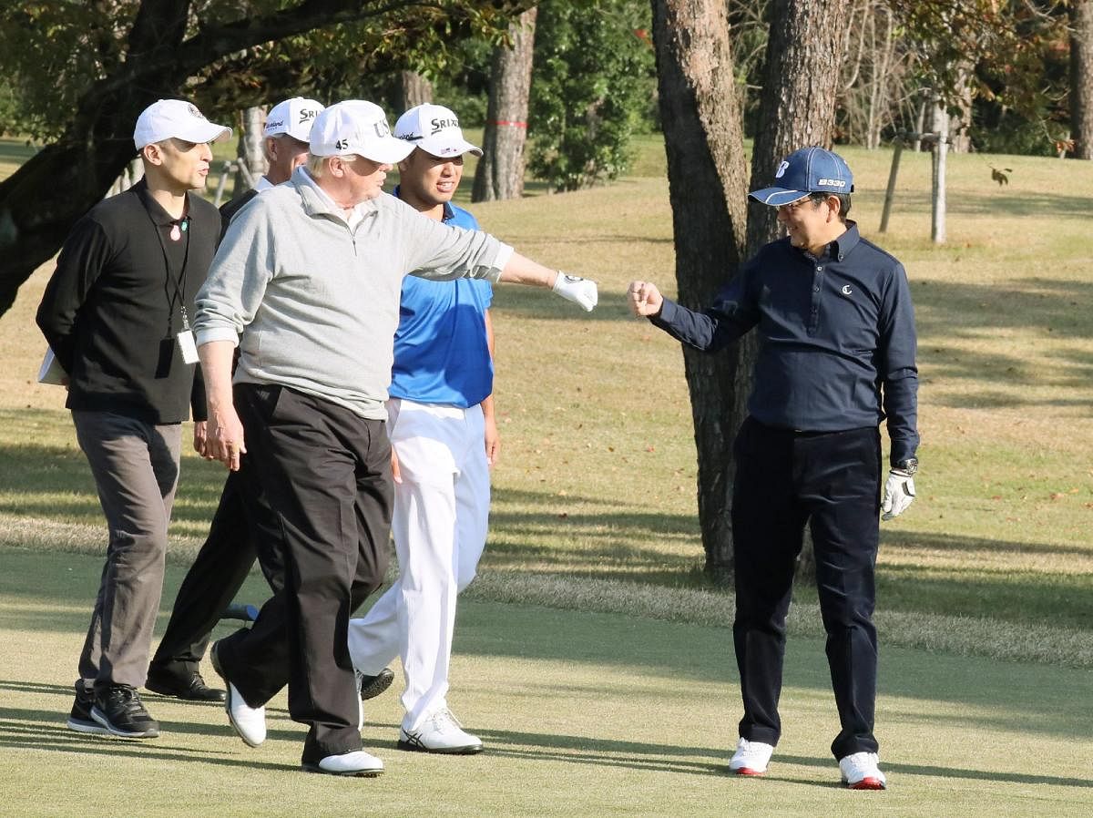 TOPSHOT - In this handout picture released by Japan's Cabinet Public Relations Office via Jiji Press, US President Donald Trump (C) gestures to Japanese Prime Minister Shinzo Abe (R) while playing golf with Japanese professional golfer Hideki Matsuyama (2