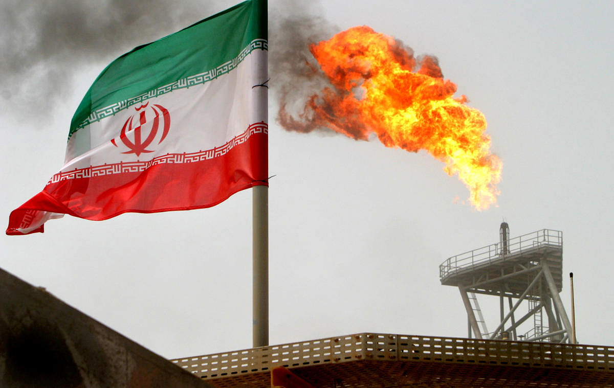 FILE PHOTO: A gas flare on an oil production platform in the Soroush oil fields is seen alongside an Iranian flag in the Persian Gulf, Iran, July 25, 2005. REUTERS/Raheb Homavandi/File Photo