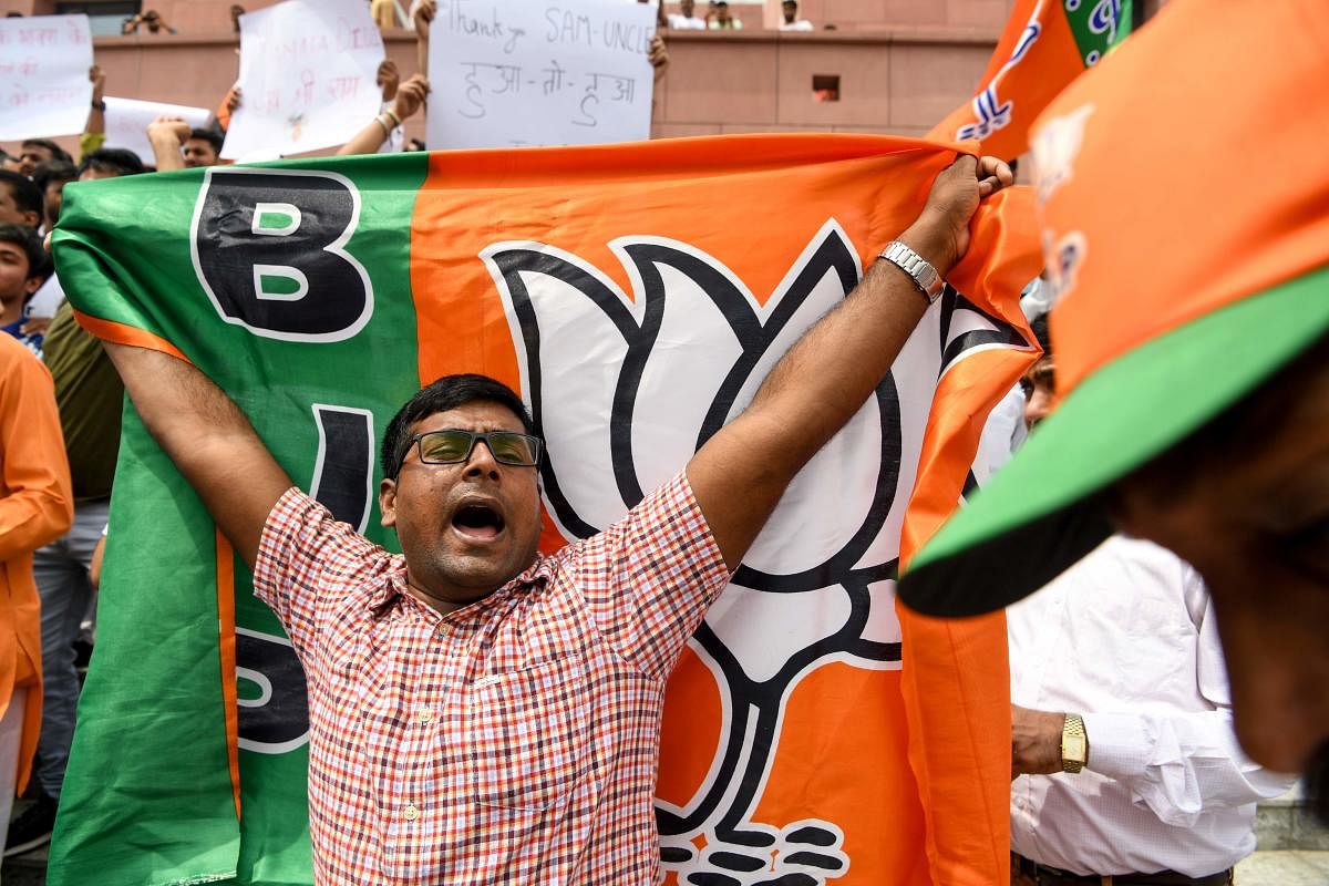 An Indian Bharatiya Janata Party (BJP) supporter shouts slogans and holds the party flag as he celebrates on the vote results day for India's general election in New Delhi on May 23, 2019. - Prime Minister Narendra Modi looked on course on May 23 for a ma