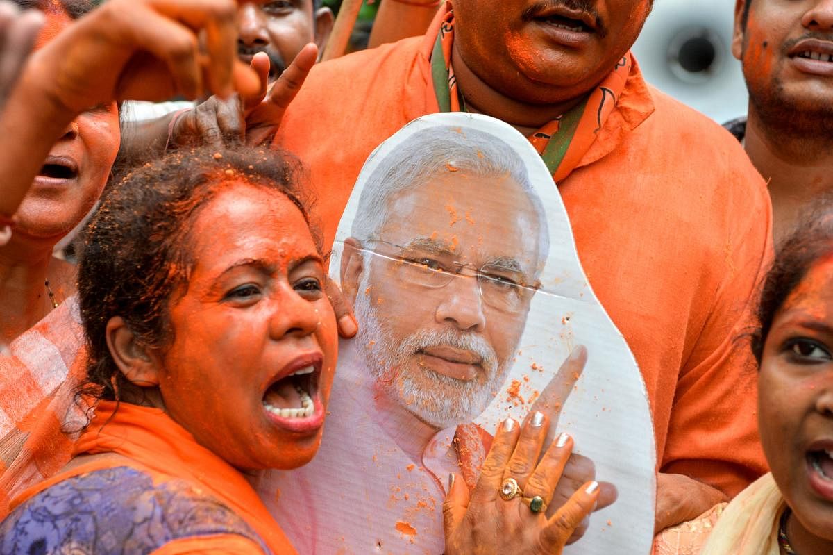 An Indian supporter of Bharatiya Janata Party (BJP) shouts slogans and a cut-out of Indian Prime Minister Narendra Modi as she celebrates on the vote results day for India's general election in Siliguri on May 23, 2019. - Indian Prime Minister Narendra Mo