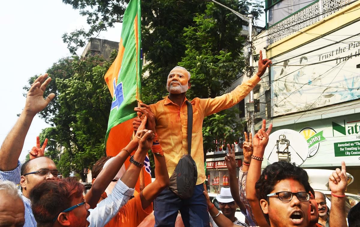 An Indian supporter (C) of the Bharatiya Janata Party (BJP) wearing a mask of Prime Minister Narendra Modi celebrates with others during the vote results day of India's general election, in Kolkata on May 23, 2019. - India's Prime Minister Narendra Modi claimed victory May 23 in the country's elections, promising an "inclusive" future after his Hindu nationalist party appeared headed for a landslide win. (Photo by Dibyangshu SARKAR / AFP)