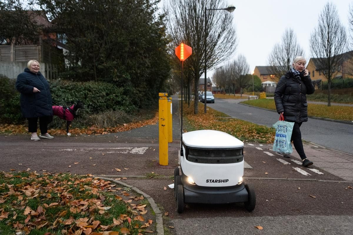A delivery robot passes members of the public as it makes a home delivery of groceries from the Co-op food store on November 23, 2018 in Milton Keynes, England. Photographer: Leon Neal/Getty Images Europe